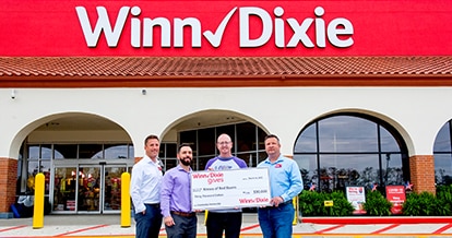 Group of people in front of a Winn-Dixie store holding a big check